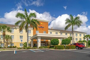A Comfort Suites hotel with a covered entrance, palm trees, and a parking lot.