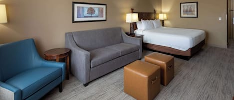 A hotel room with a bed, a sofa, a small table, and two storage boxes.