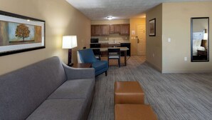 A compact living space with a sofa, a blue armchair, a dining table, and a kitchen area.