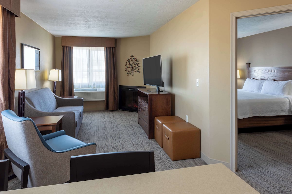 Une chambre d’hôtel avec un lit, une télévision, un bureau, une chaise et une petite table.