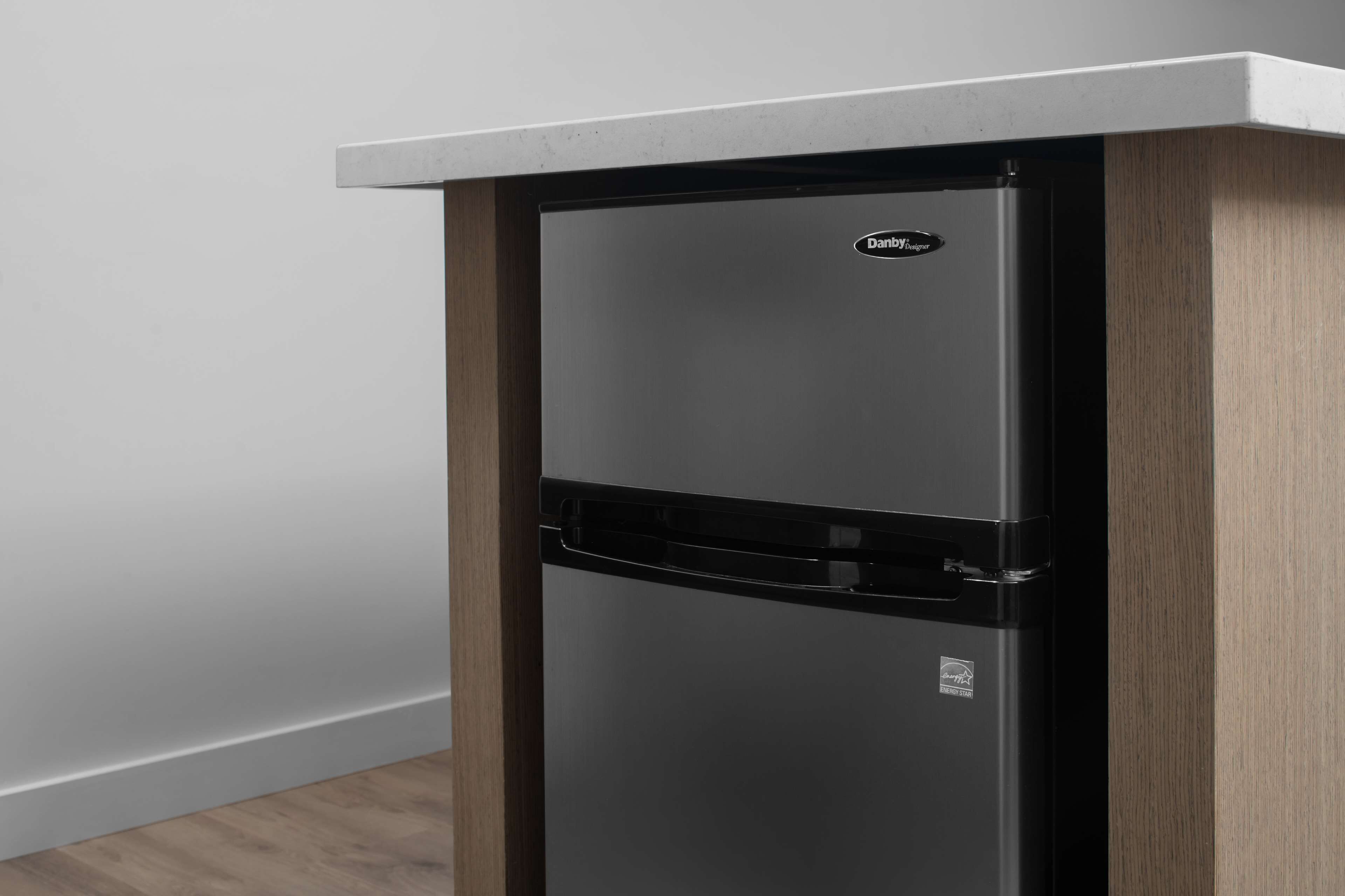 A black refrigerator with a wooden cabinet and a white countertop above it.