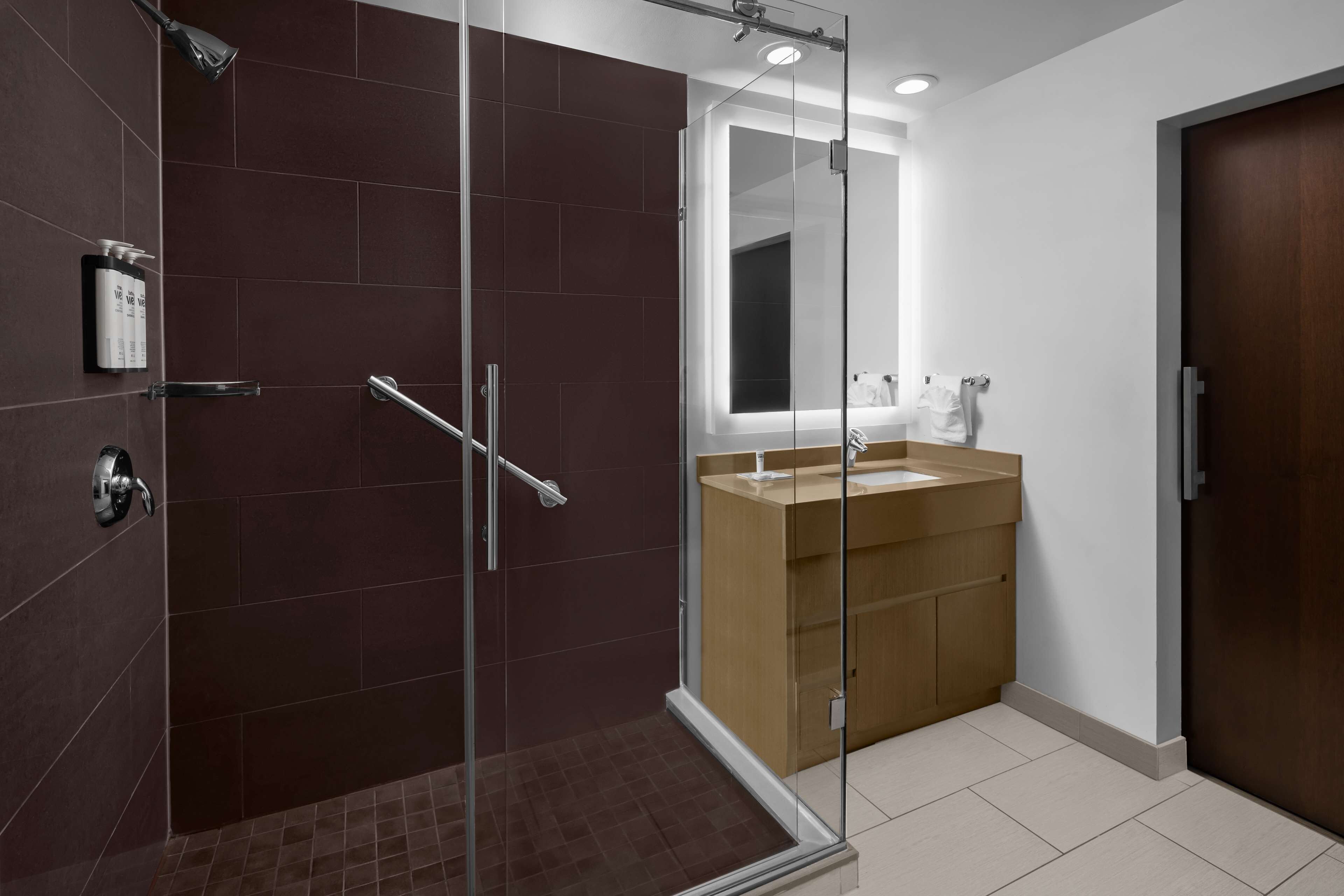 Une salle de bain moderne avec une douche à parois de verre, un meuble-lavabo en bois et un grand miroir.