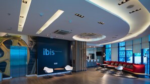 A modern interior with a reception desk, seating area, and a large window offering a view. - ibis Passo Fundo Centro Hotel (Passo Fundo)