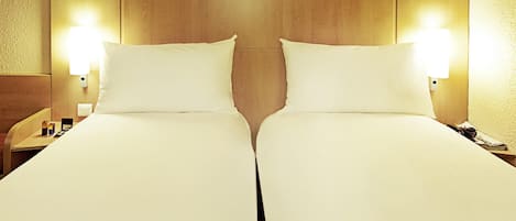 A double bed with two pillows and a wooden headboard.