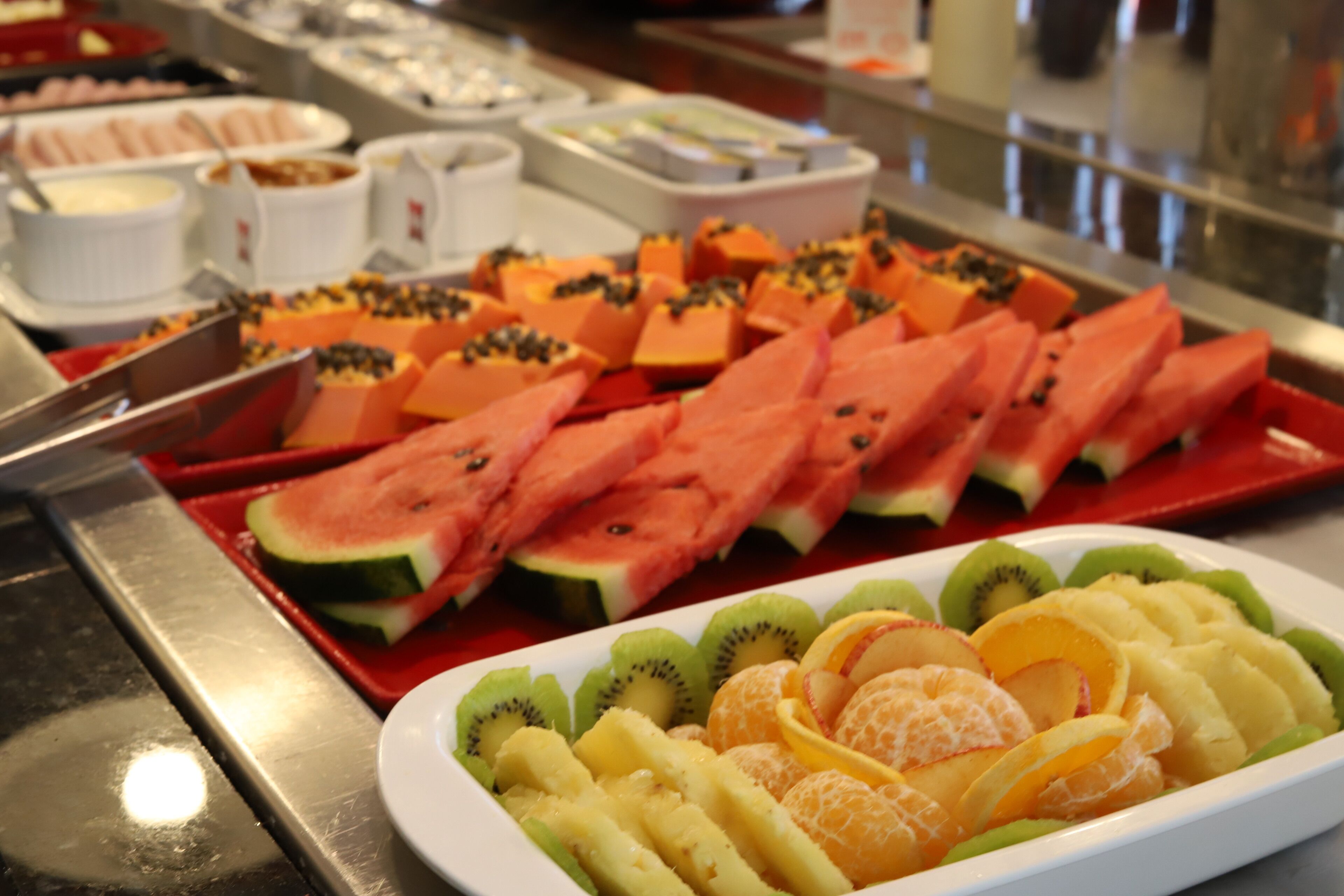 Un bufé con diversas frutas y verduras, incluyendo sandía, kiwi y naranjas.