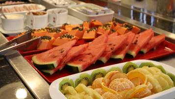 Un bufé con diversas frutas y verduras, incluyendo sandía, kiwi y naranjas.