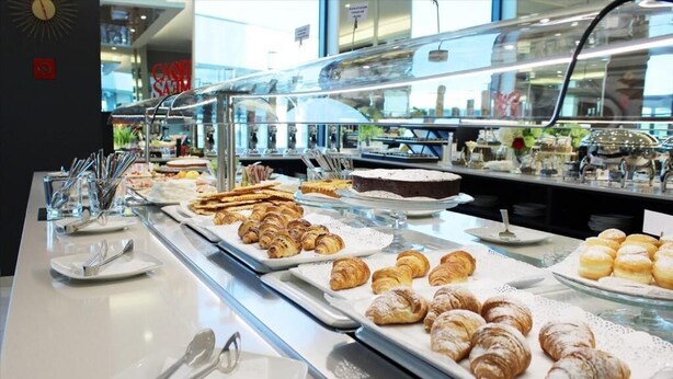 A buffet with various pastries and desserts, including croissants and cakes, displayed on trays. - AN HOTEL MILANO MELEGNANO (Carpiano)