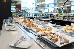 A buffet with various pastries and desserts, including croissants and cakes, displayed on trays. - AN HOTEL MILANO MELEGNANO (Carpiano)