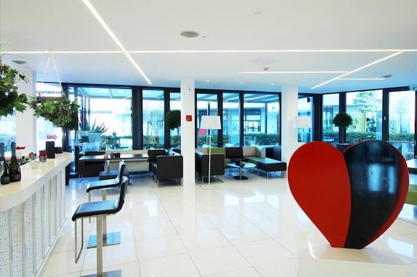 A modern lobby with a reception desk, seating area, and large windows.