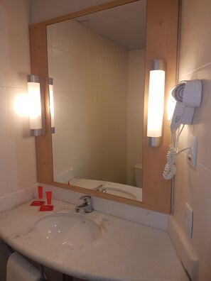 A bathroom with a sink, mirror, and hairdryer.