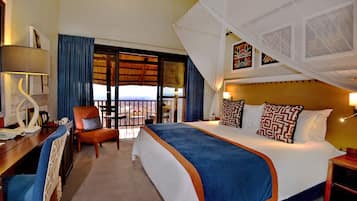 A hotel room with a large bed, a desk, a chair, and a balcony with a view.