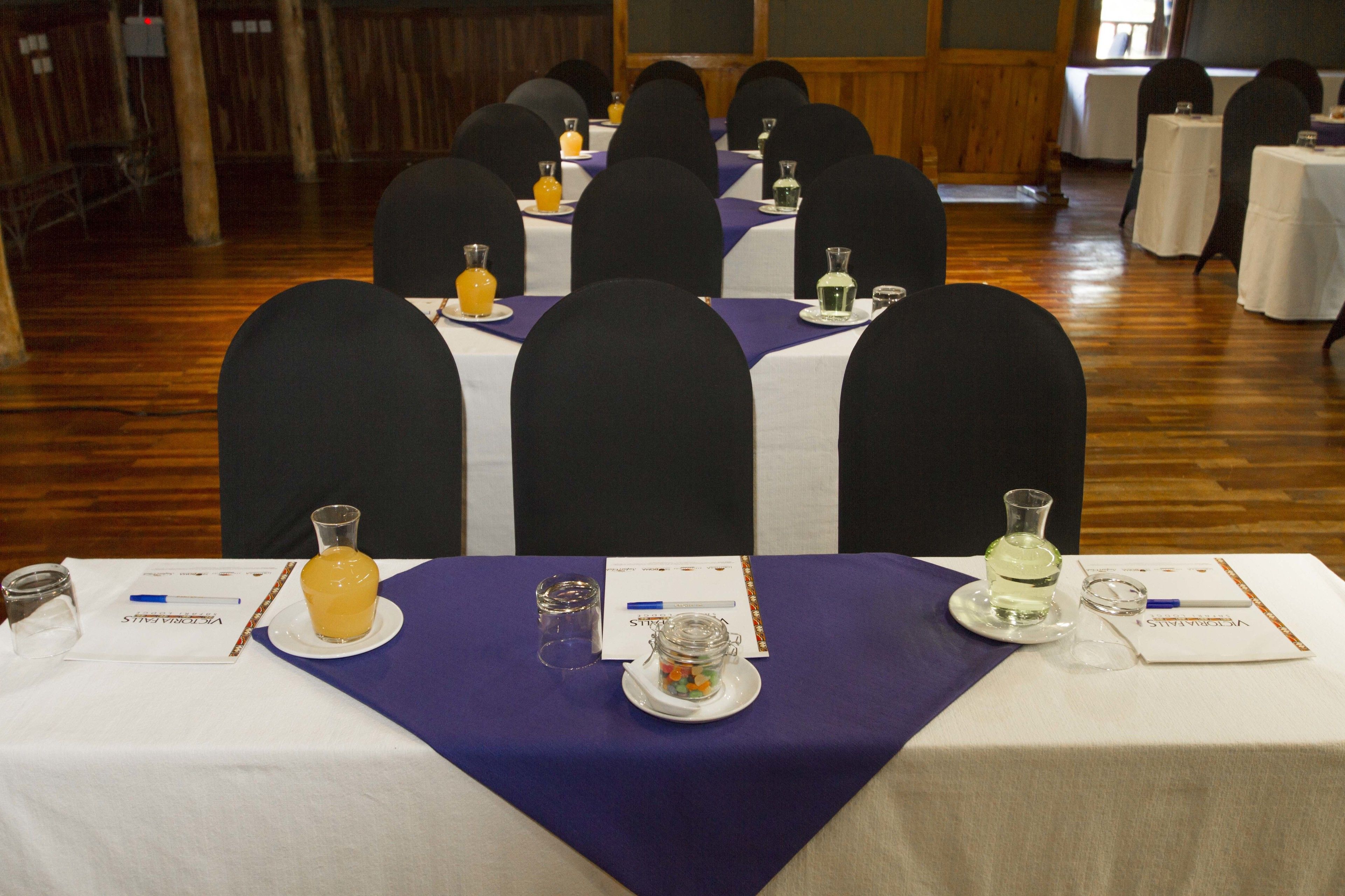 A conference room with tables set for a meeting, each with nameplates, water bottles, and a small glass container.
