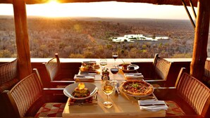 A dining table set for a meal with a view of a landscape.