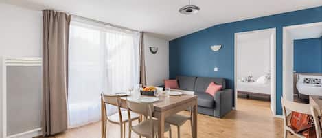 Una sala moderna con comedor, sofá y una cama al fondo.