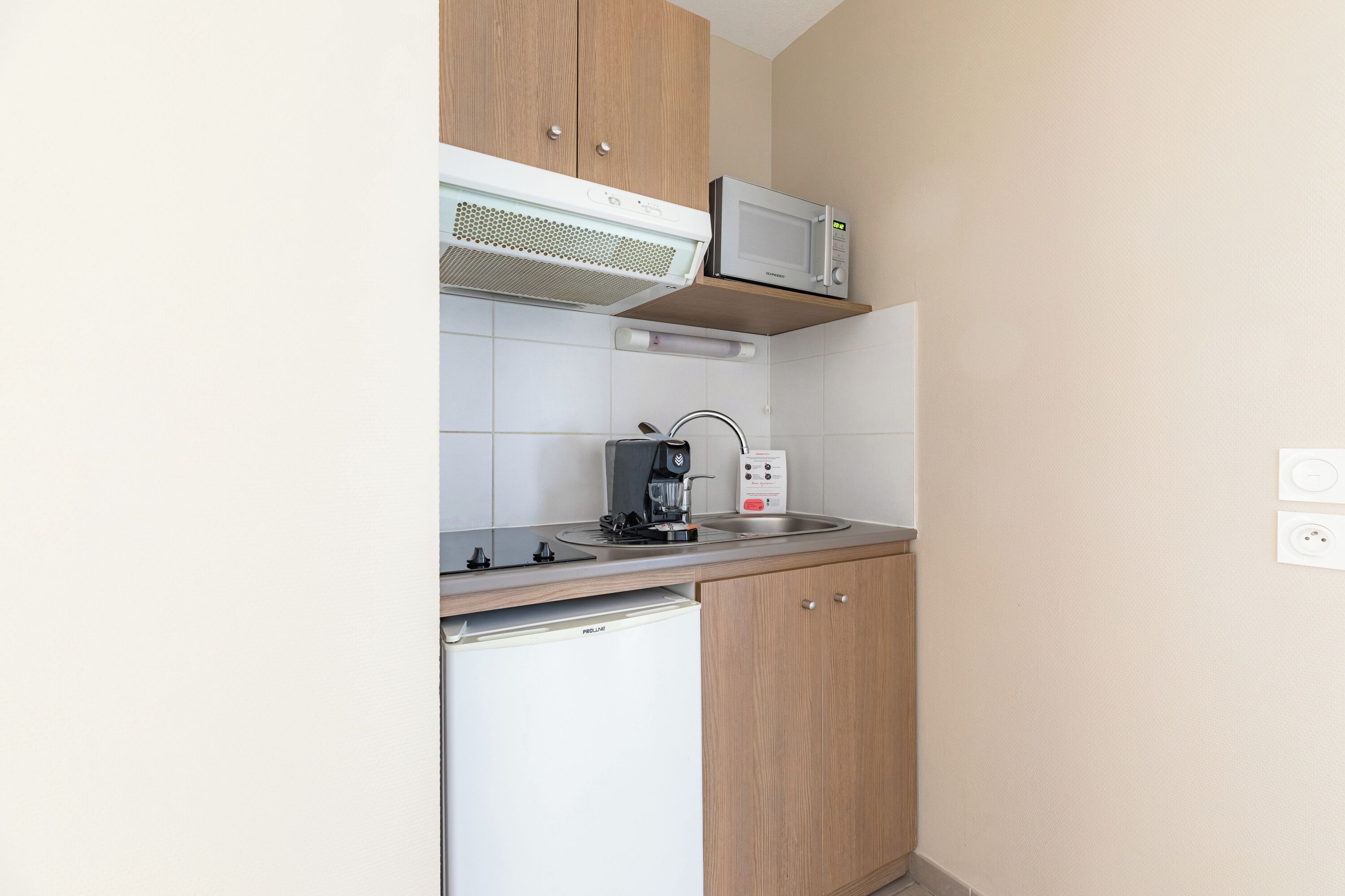 A compact kitchen with a microwave, coffee maker, and a small refrigerator.