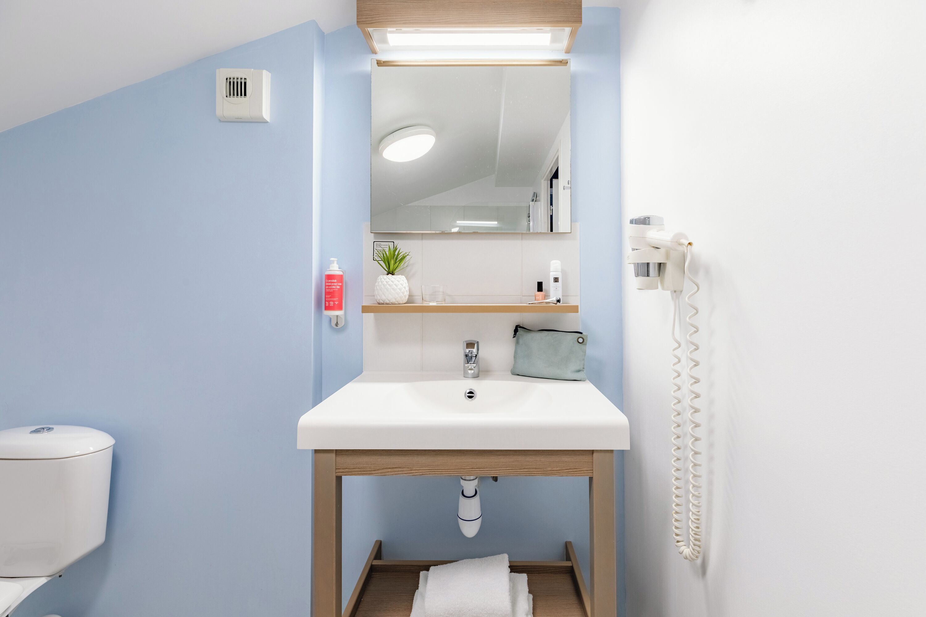 A bathroom with a white sink, a mirror, a towel rack, a toilet, and a shower.