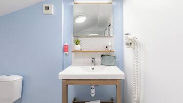 A bathroom with a white sink, a mirror, a towel rack, a toilet, and a shower.
