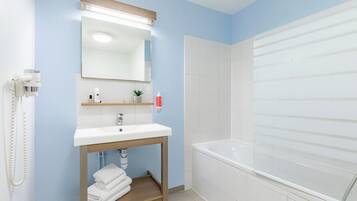 A bathroom with a white sink, mirror, and bathtub. There is a towel rack and a small shelf with toiletries.