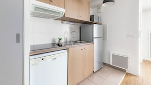 A modern kitchen with wooden cabinets, a stainless steel sink, and a built-in dishwasher. - Appart'City Confort Niort Centre (Niort)