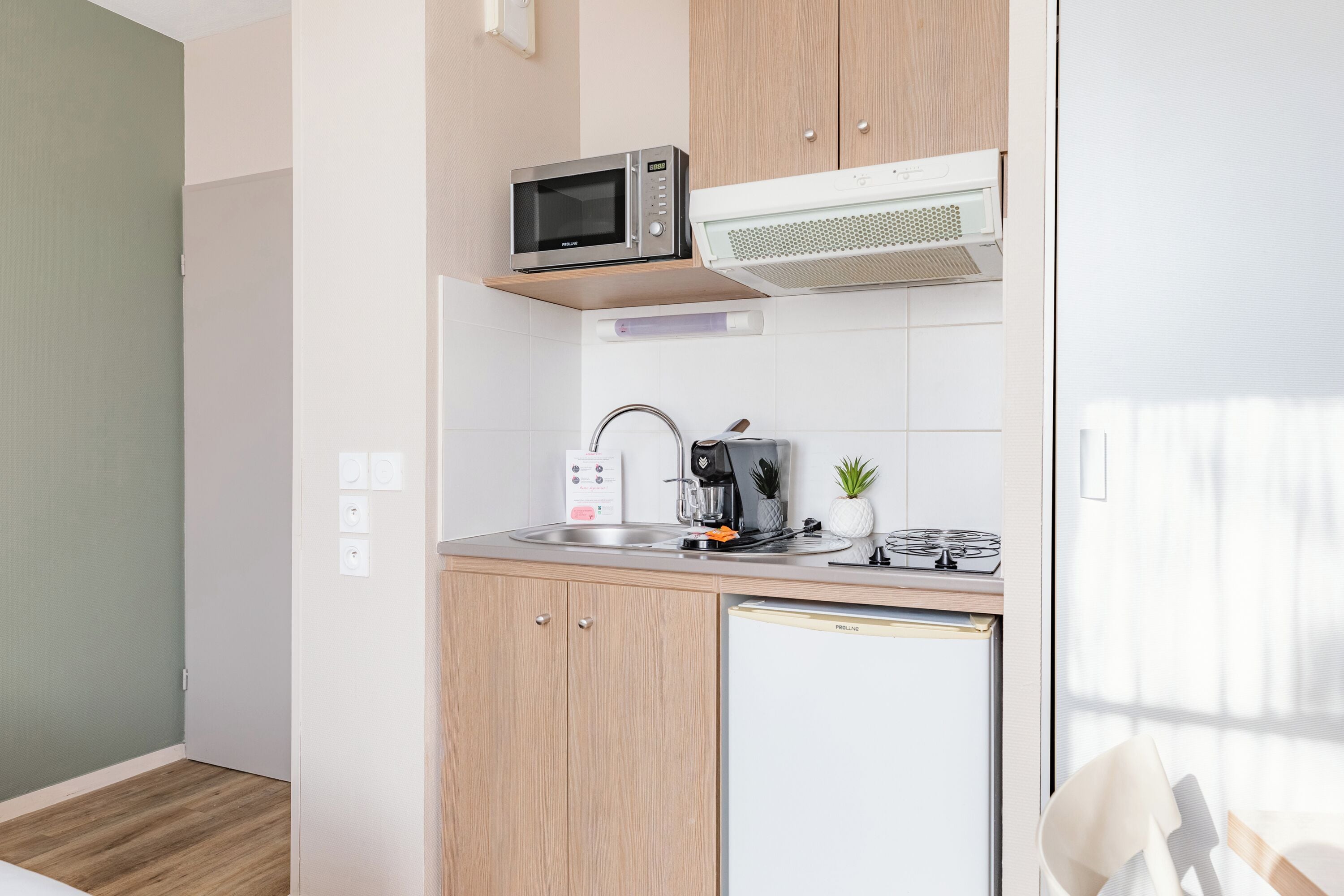 A compact kitchen with a microwave, coffee maker, and a small refrigerator.