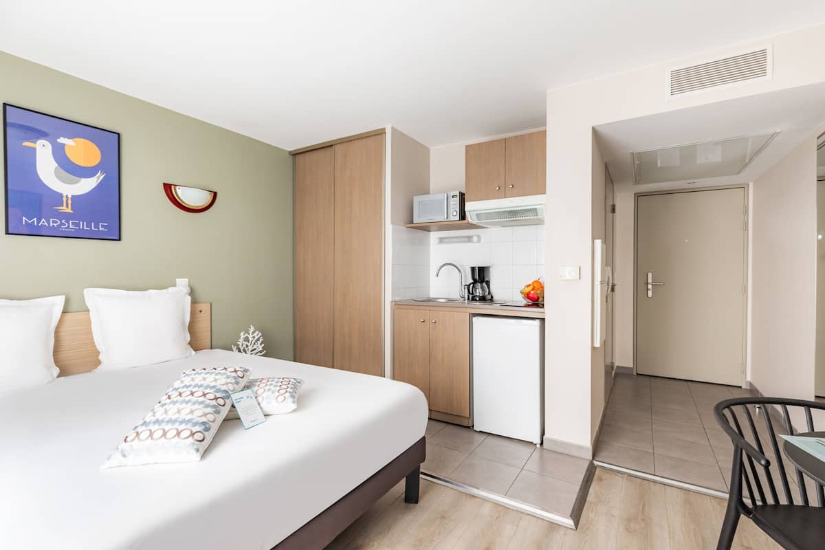 Ein Hotelzimmer mit Bett, einer kleinen Küchenzeile und einem Essbereich.