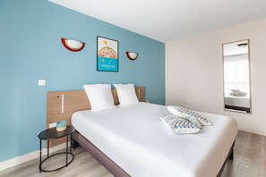 Ein Hotelzimmer mit Bett, einem kleinen Tisch, einer Wandleuchte und einem Poster.