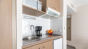 A modern kitchen with stainless steel appliances, a built-in microwave, and a fruit bowl on the counter. - Appart'City Classic Marseille Euromed (Marseille)