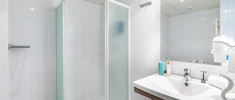 A modern bathroom with a glass-enclosed shower, a white sink, and a mirror above it.