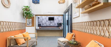 A modern hotel lobby with a sofa, chairs, a small table, and a reception desk.