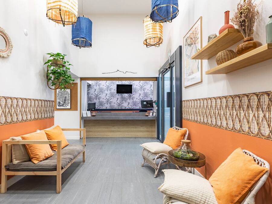 En modern hotellobby med en soffa, stolar, ett litet bord och en receptionsdisk.