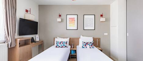 Habitación de hotel moderna con dos camas individuales, un escritorio con televisor de pantalla plana, un aparador de madera y un ventanal con cortinas.