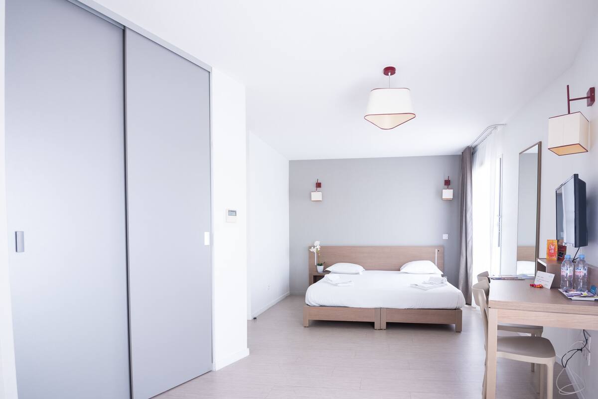 A modern hotel room with a large bed, a desk, and a TV.