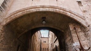 Un arco de piedra que da paso a un patio con un farol y un adorno de ancla.
