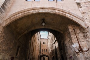 A stone archway leading to a courtyard with a lantern and an anchor decoration. - Zenitude Hôtel - Résidences Narbonne Centre (Narbonne)