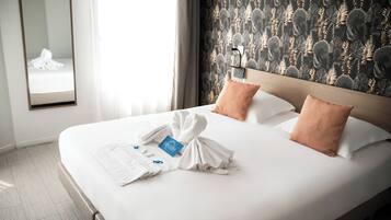 Habitación de hotel con una cama bien tendida, un espejo y una pared con un diseño de hojas.