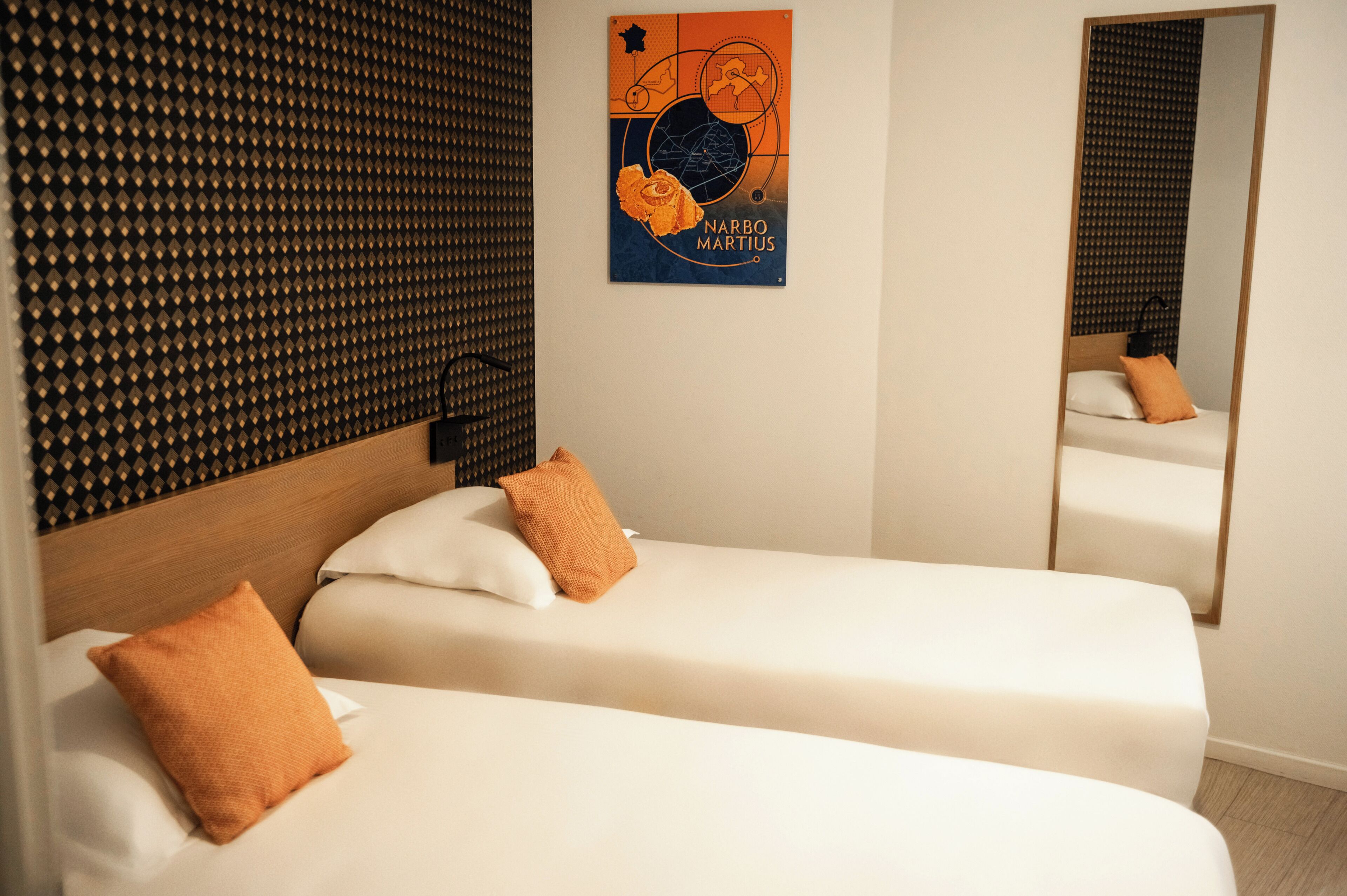 Une chambre d’hôtel avec deux lits simples, une tête de lit en bois et un miroir fixé au mur.