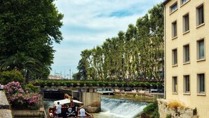 Un bote en un río con una cascada, rodeado de vegetación y un puente.