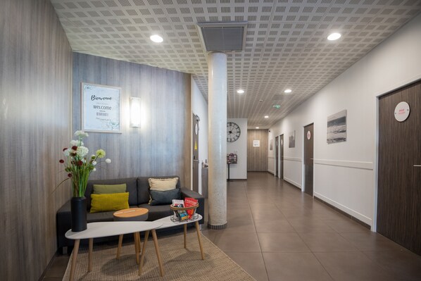 Una moderna zona de recepción con un sofá, una mesa de centro y un jarrón con flores.