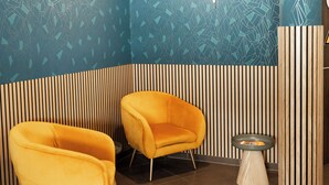 Una habitación con dos sillas amarillas, una mesita redonda y un enjute decorativo con un diseño geométrico.