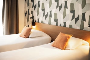 A hotel room with two beds, a wooden headboard, and a geometric-patterned wall. - Zenitude Hôtel - Résidences Narbonne Centre (Narbonne)