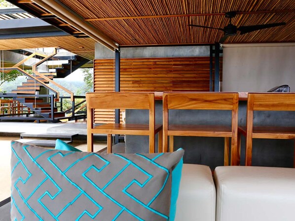 Un espace extérieur moderne, aménagé avec des chaises et un canapé en bois, un escalier et une vue sur un paysage montagneux.