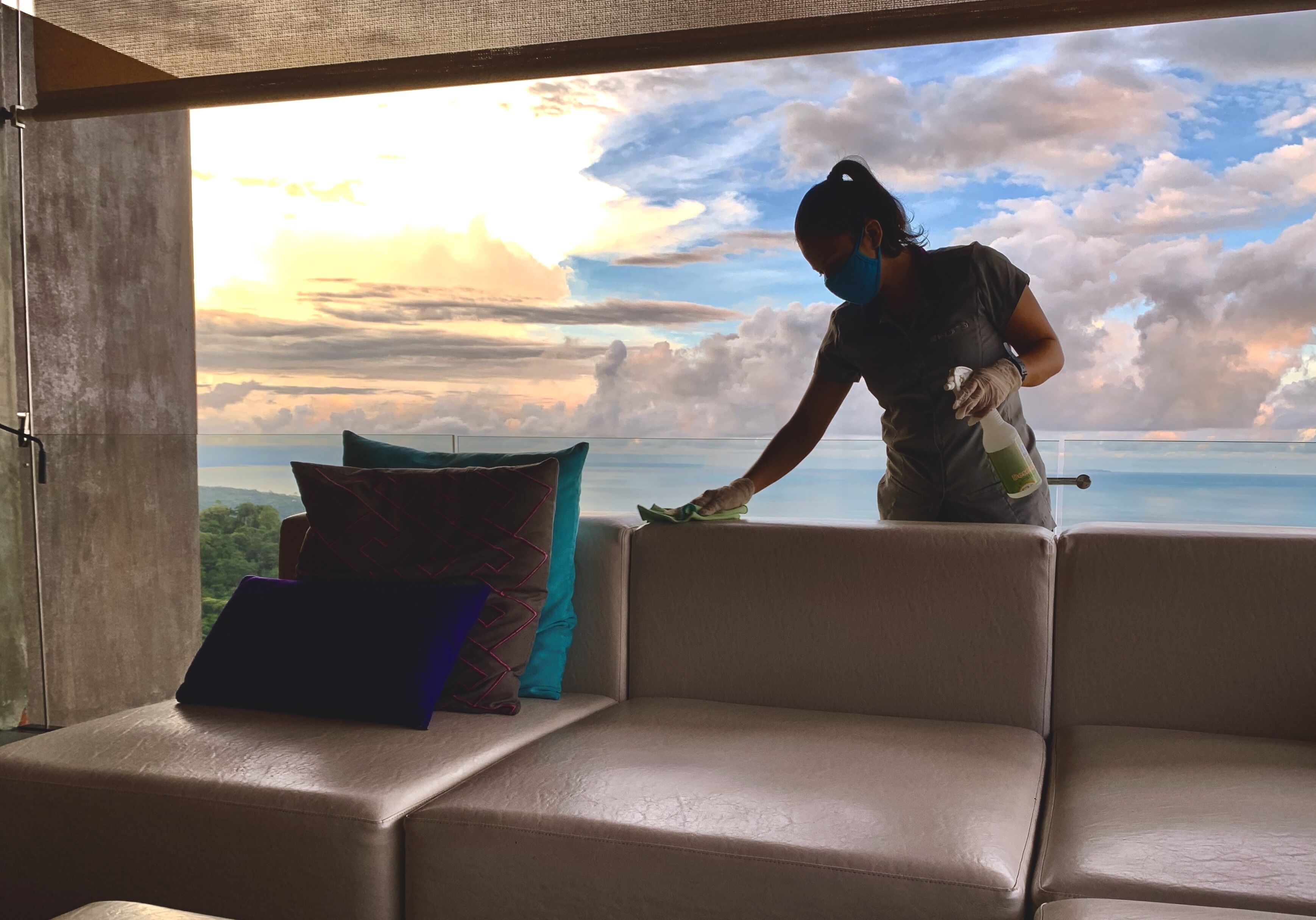 A person cleaning a leather sofa with a view of the sky and clouds.