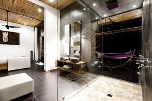 Un baño moderno con suelo de piedra, un sofá blanco, un tocador de madera y una hamaca.