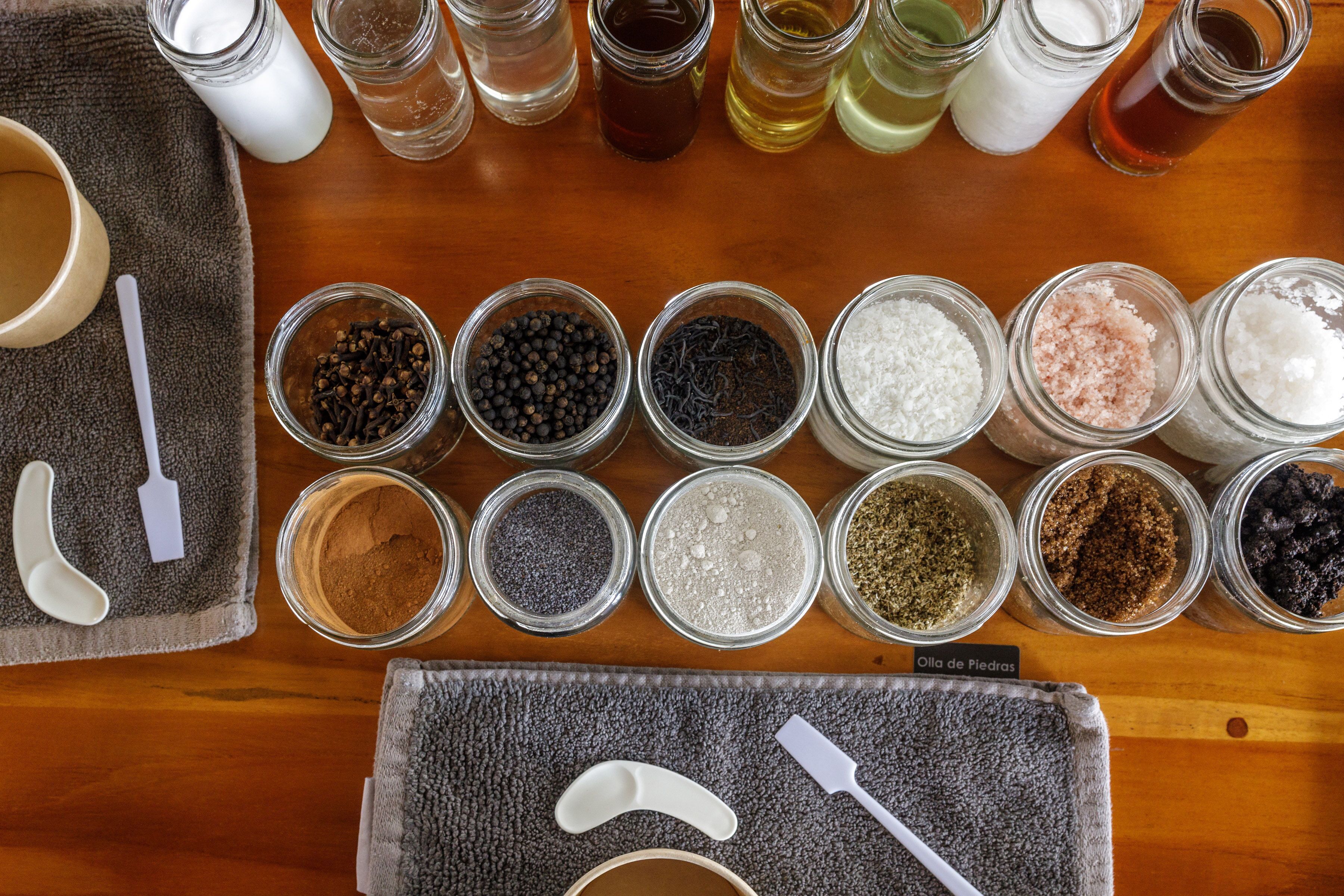 A variety of spices and kitchen tools arranged on a wooden table.