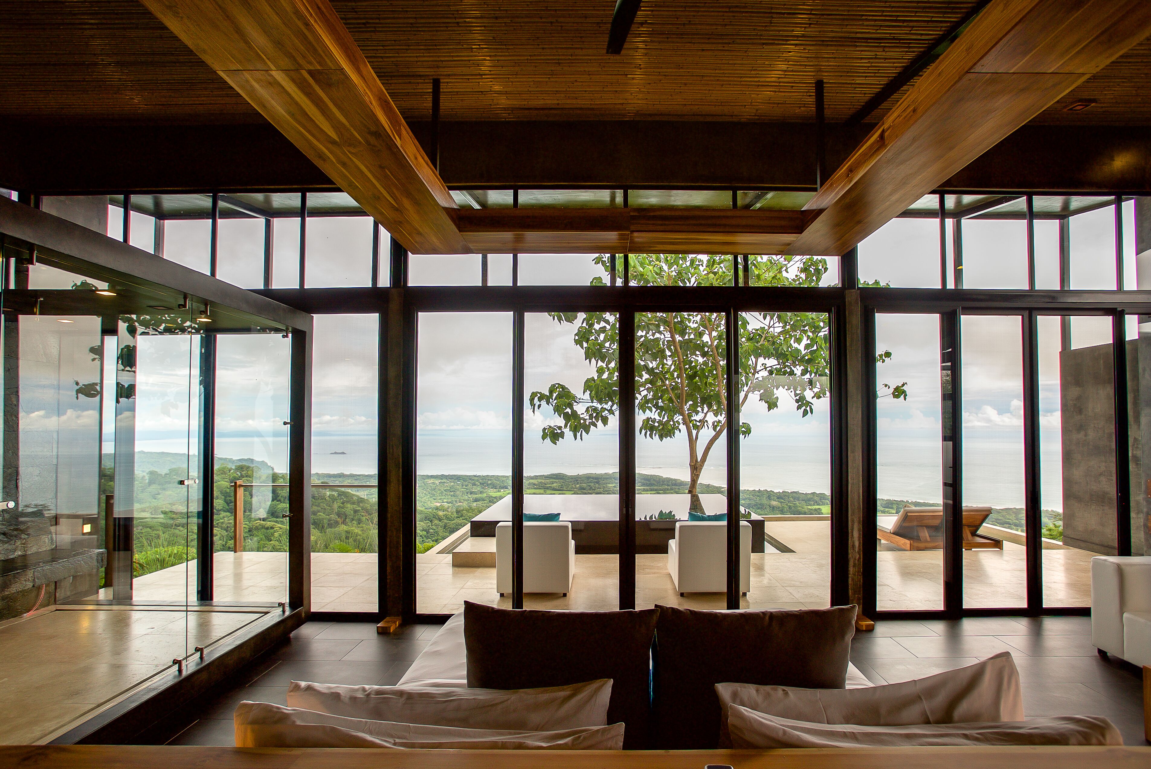 A spacious room with large windows offering a view of a lush landscape and a body of water.