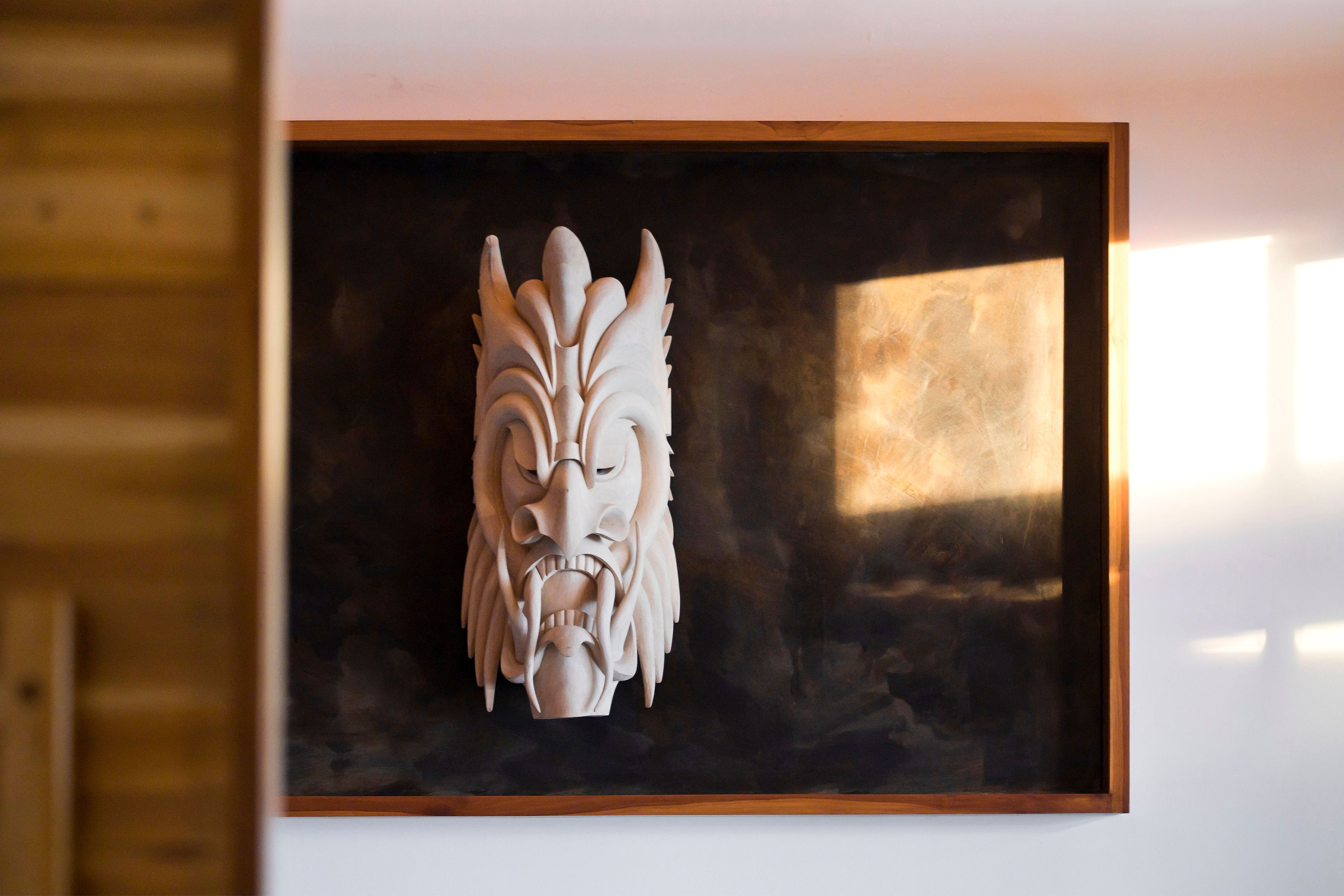 A framed sculpture of a stylized animal head.