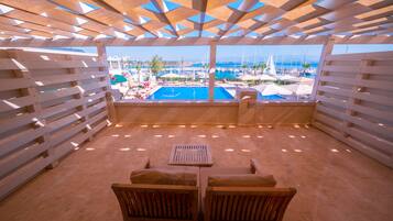 A wooden deck with a pool view, wooden furniture, and a clear sky.