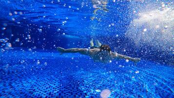 An underwater view of a swimming pool with a person swimming.