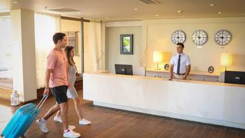A hotel reception area with a wooden floor, a reception desk, and three wall clocks.