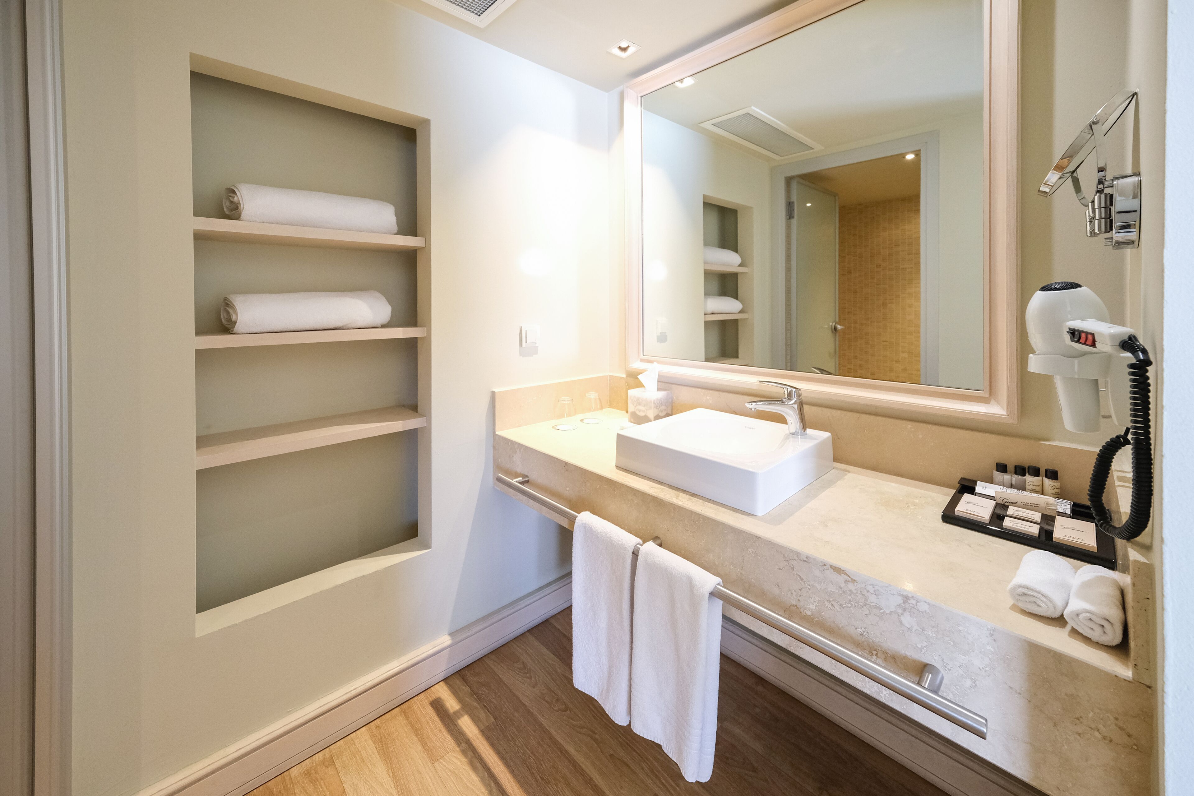 A modern bathroom with a large mirror, a sink, and a towel rack with towels.